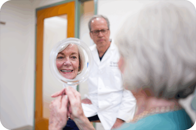 a patient looks at her new smile in a mirror